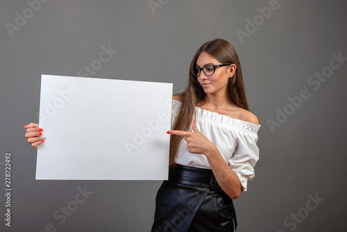 Beautiful woman holding a blank billboard isolated on gray background - inage photo