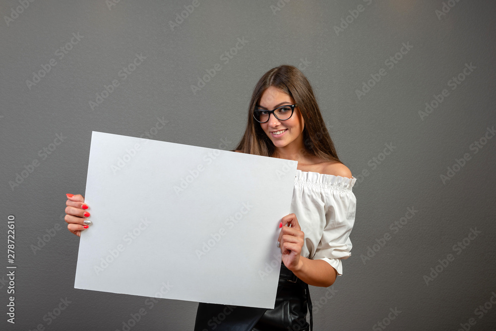 Naklejka premium Beautiful woman holding a blank billboard isolated on gray background - inage