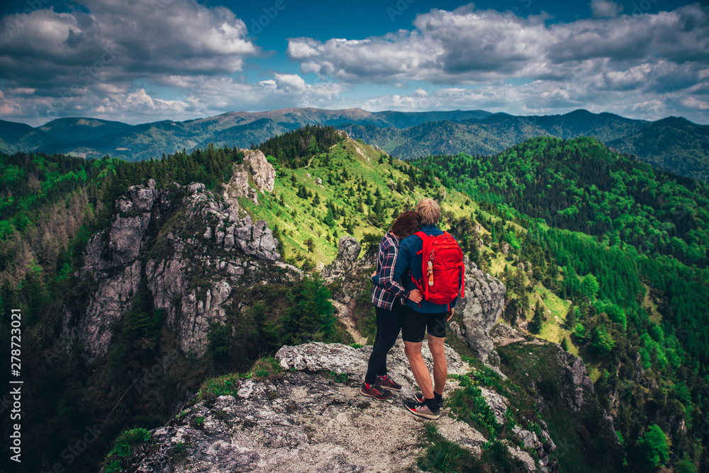 Couple standing together at the top of the hill. Romantic photo, adventure in two, couple in mountains. Beautiful rocky hills in background