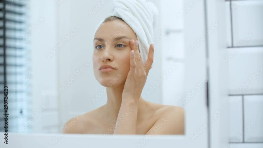 Closeup of beautiful young woman examining herself in front of mirror. Closeup of beautiful young woman examining herself in front of mirror.