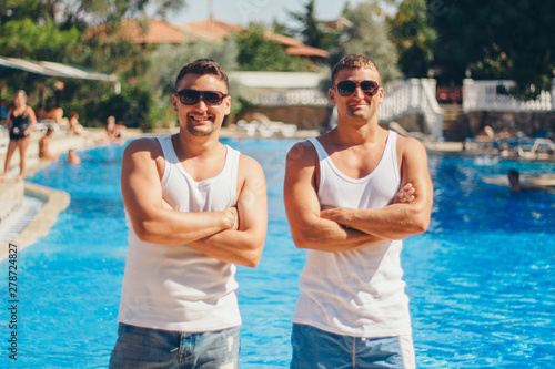 the concept of recreation, tourism - two smiling inflated men with glasses having fun by the pool