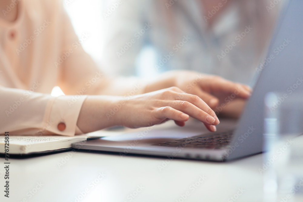 Girls dressed in casual discuss work issues, hands on a laptop Girls dressed in casual discuss work issues, hands on a laptop