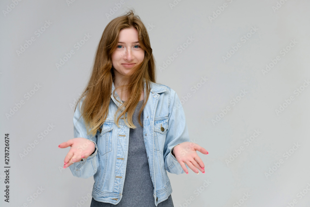 Portrait to waist of a young pretty brunette girl woman with beautiful long hair on a white background in a jacket from jeans. He talks, smiles, shows his hands with emotions in various poses. Portrait to waist of a young pretty brunette girl woman with beautiful long hair on a white background in a jacket from jeans. He talks, smiles, shows his hands with emotions in various poses.