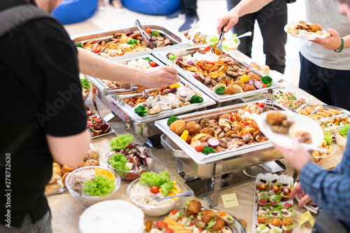Fotografie Close up of hands scooping food. Buffet catering meal concept.