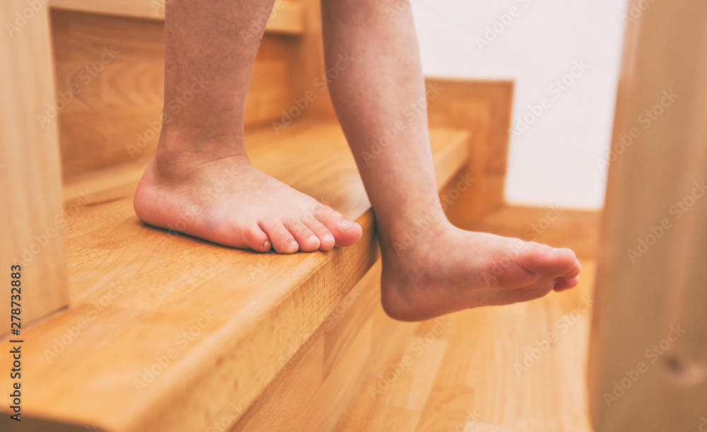 The child is moving down through the wooden stairs in home The child is moving down through the wooden stairs in home