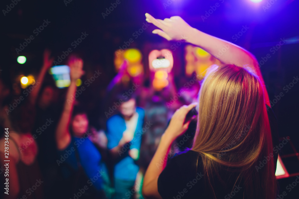 Beauty model girl singer with a microphone singing and dancing over holiday glowing background. Karaoke party singer. Disco party. Celebration. - obrazy, fototapety, plakaty 