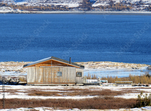 Wood cabin by the blue water in Nunavik in the Fall