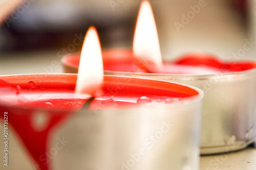 Closeup of burning red candle on bokeh background