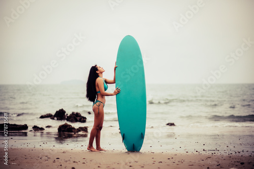 Beautiful asian sexy woman with surfboard on the beach.