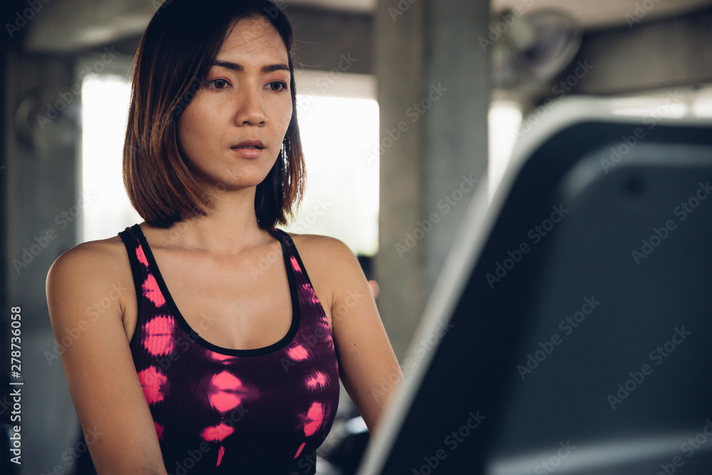 Asian woman jogging on treadmill in the gym fitness club. Asian woman jogging on treadmill in the gym fitness club.