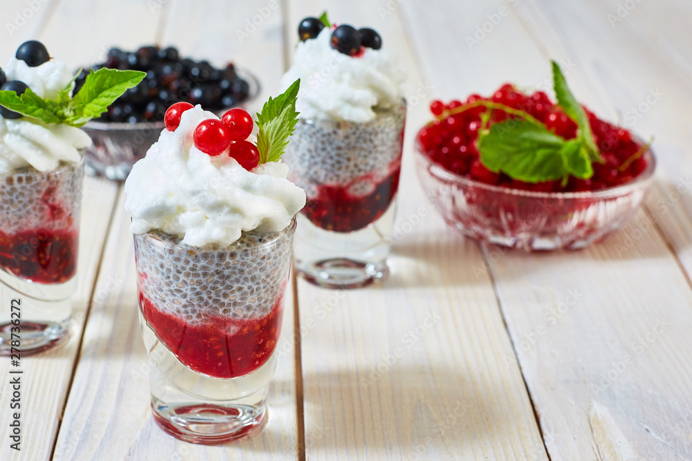 On the table standing a glass of black currant dessert, cream and chia seeds. On the table standing a glass of black currant dessert, cream and chia seeds.