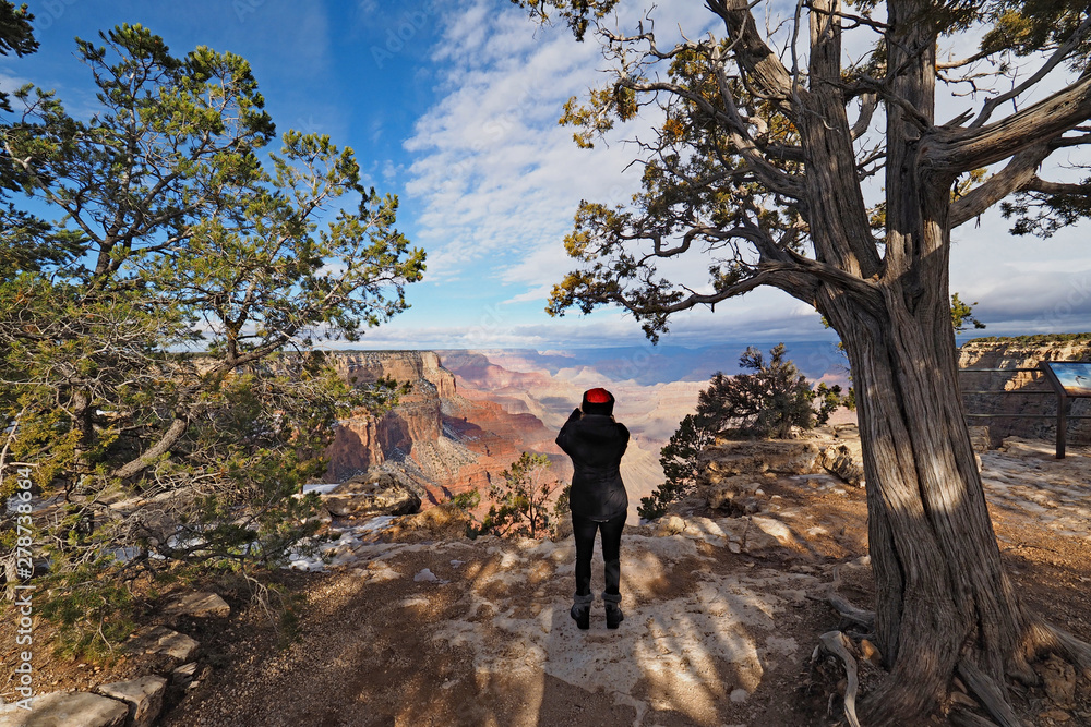 Woman photographing the canyon from the South Rim Trail in Grand Canyon National Park, Arizona, in winter.