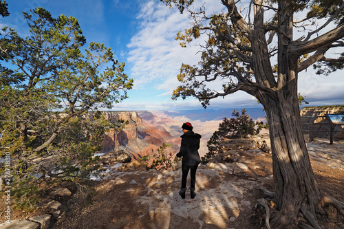 Woman photographing the canyon from the South Rim Trail in Grand Canyon National Park, Arizona, in winter.