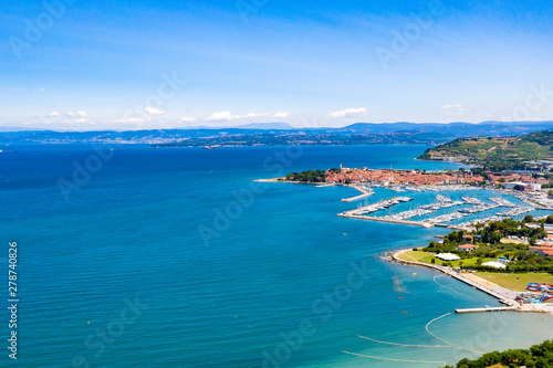 Aerial view of the seaside with buildings and greens trees over the ocean © magdal3na