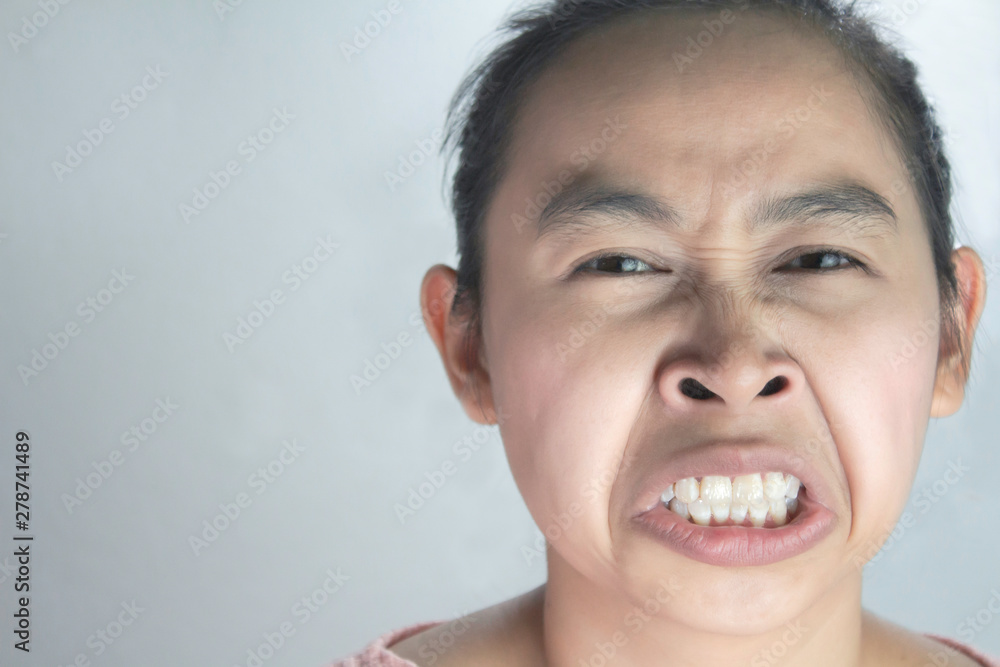 Portrait of Asian woman with hate and disgusting face in pink shirt on grey background. Portrait of Asian woman with hate and disgusting face in pink shirt on grey background.