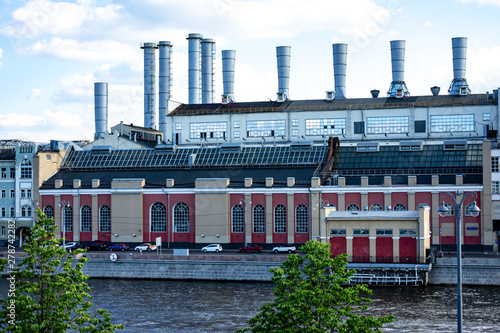 View from Zaryadie park on factory pipes of oldest power station in Moscow on Raushskaya Embankment. In front of power plant building concrete embankment Moscow River. Moscow, Russia, June, 2019