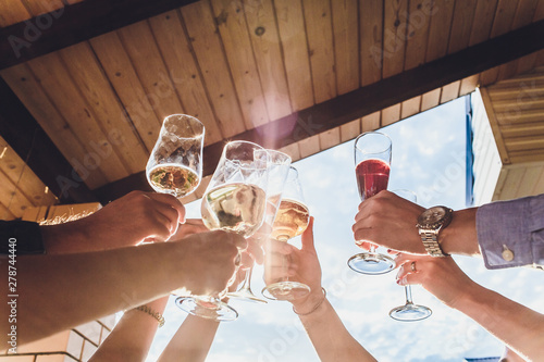 Human hands with glasses of red wine clinking them over served table. photo