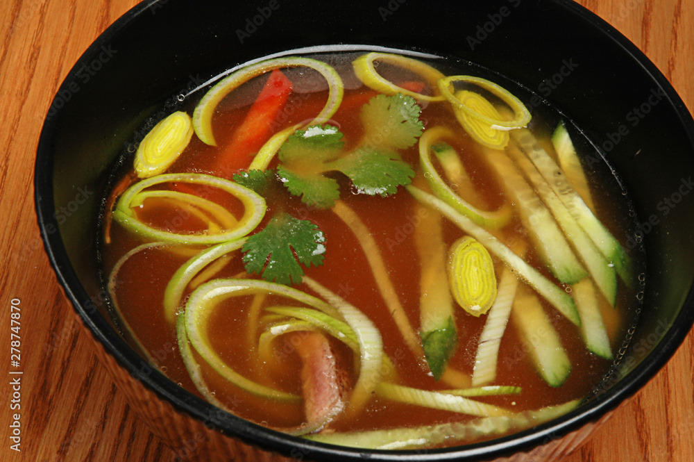 Soup with vegetables in a dark bowl on a wooden table Soup with vegetables in a dark bowl on a wooden table