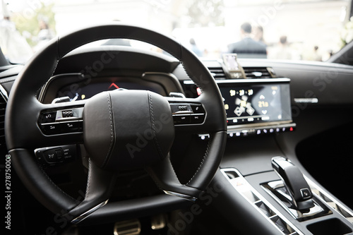 Modern luxury car Interior - steering wheel, shift lever and dashboard. Car interior luxury inside. Steering wheel, dashboard, speedometer, display. Black leather cockpit.