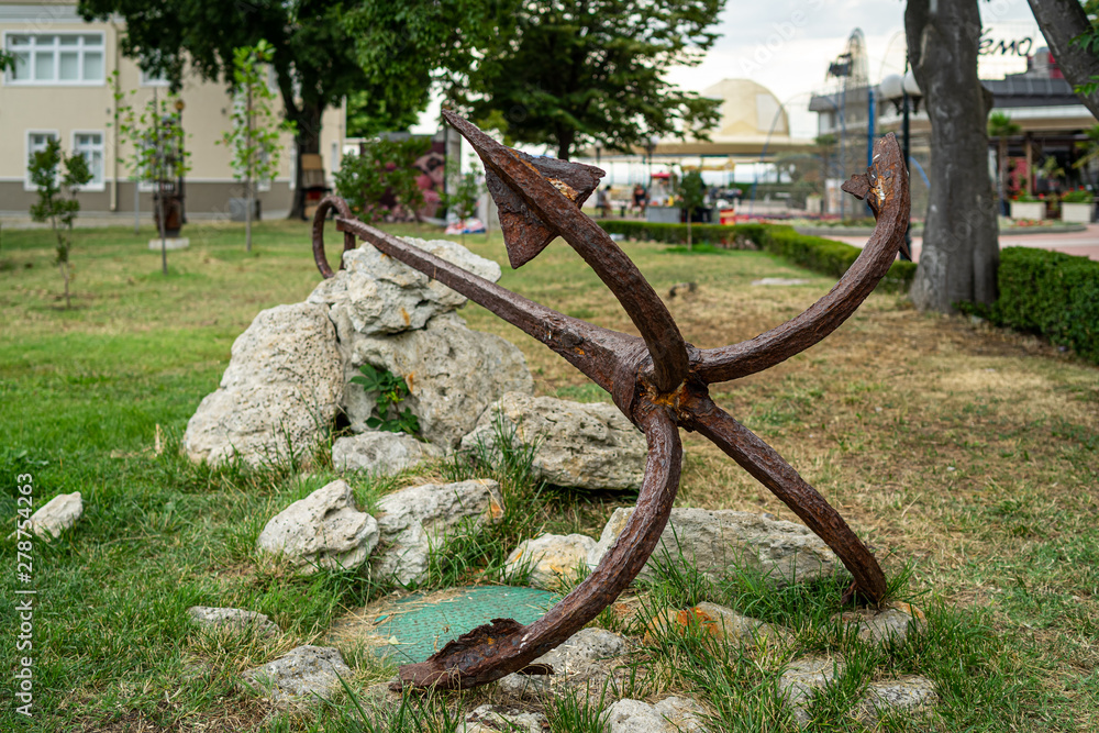 Old and rusty anchor of a fishing boat as decoration on the streets of a seaside town. Pomorie. Bulgaria.
