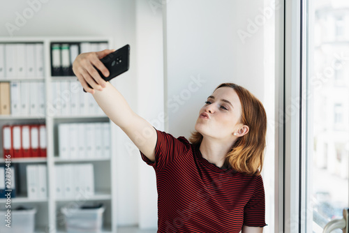 Fun young woman blowing a kiss for a selfie