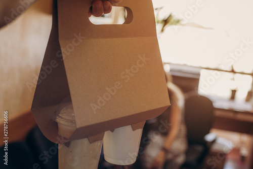 The hand of the courier is served by the owner with drinks for office workers who have ordered the delivery of coffee to the office. Coffee Take Away Order Online Delivery Concept photo