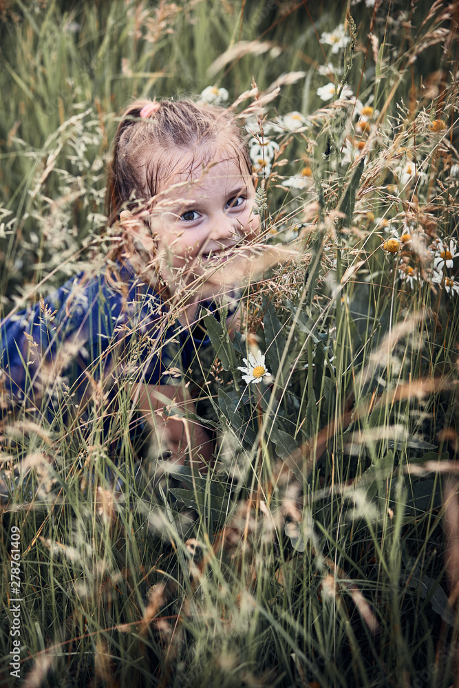 Little happy smiling kid playing in a tall grass in the countryside. Candid people, real moments, authentic situations Little happy smiling kid playing in a tall grass in the countryside. Candid people, real moments, authentic situations