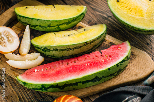 Vászonkép Different watermelons and melon, yellow and red on a wooden background