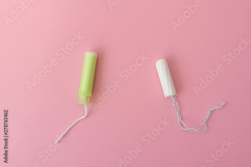 Two cotton tampons with light green applicator and without applicator on a pink background. Hygienic types of tampons. Menstruation, protection, comparison concept, flat lay, Copy space, top view