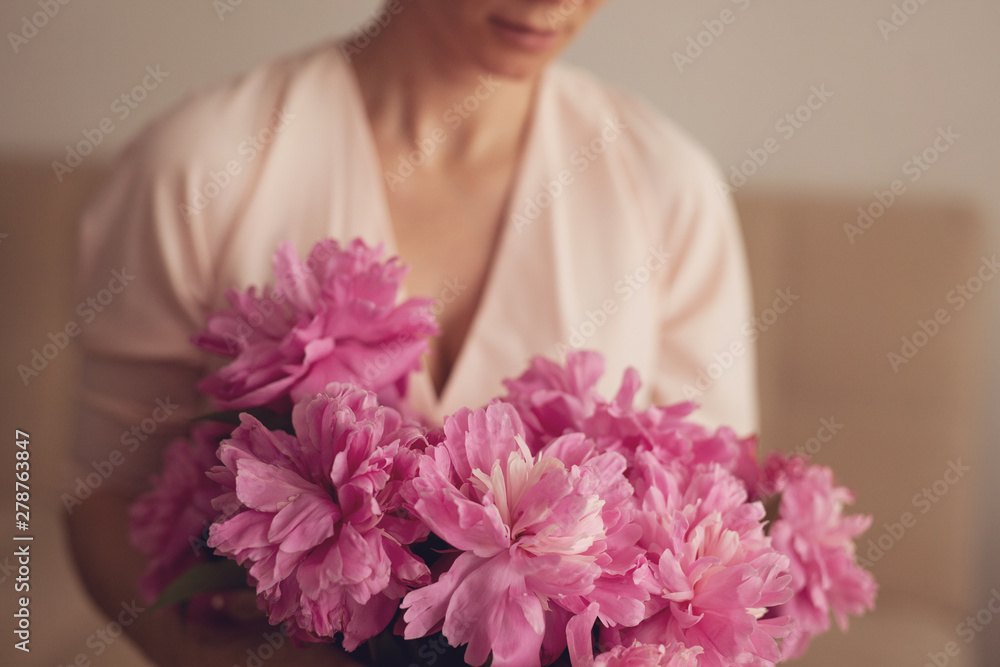 Bouquet of pink peonies in the hands of a young woman 
