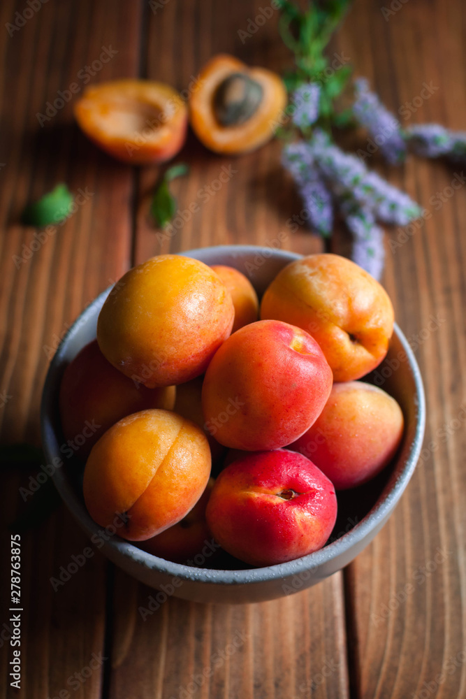 Close-up of apricots with fresh mint leaves and flowers on wooden background Close-up of apricots with fresh mint leaves and flowers on wooden background
