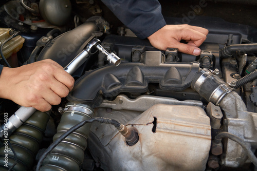 A man holds the engine of a car with a torque wrench. Auto repair service and maintenance.