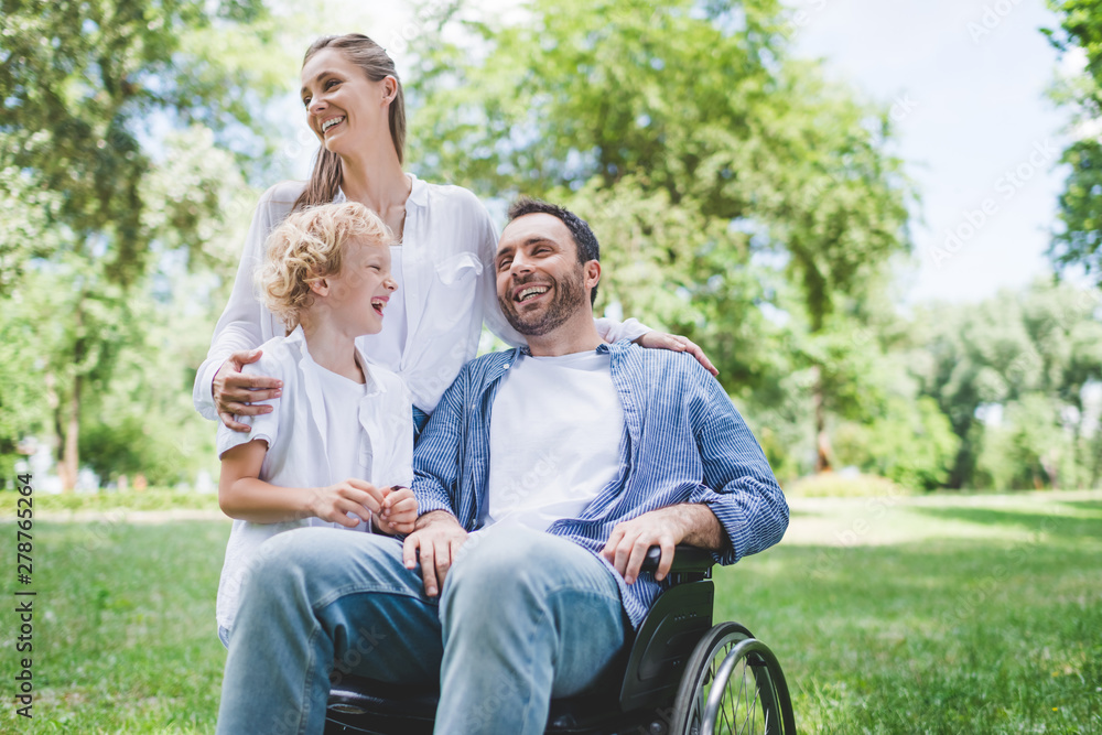 happy family with disabled father on wheelchair in park happy family with disabled father on wheelchair in park