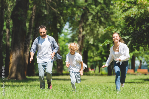 happy family running in park during daytime and looking at camera
