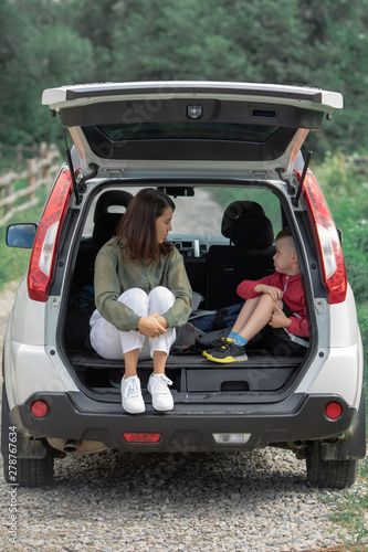 young mother with kid boy sitting in car trunk resting in summer sunny day © phpetrunina14