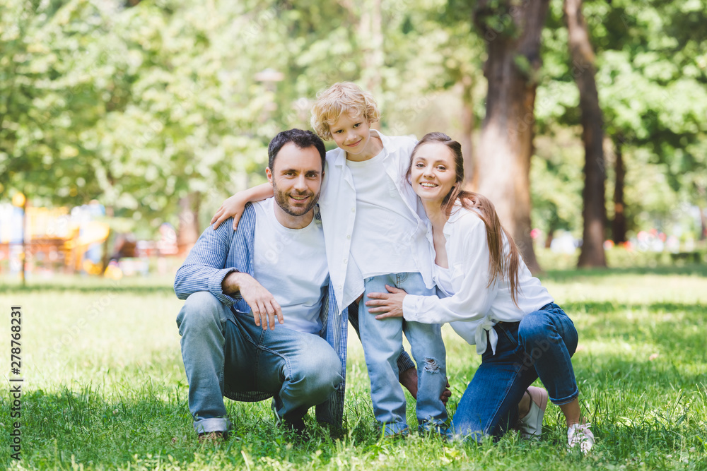 happy family looking at camera and hugging in park happy family looking at camera and hugging in park
