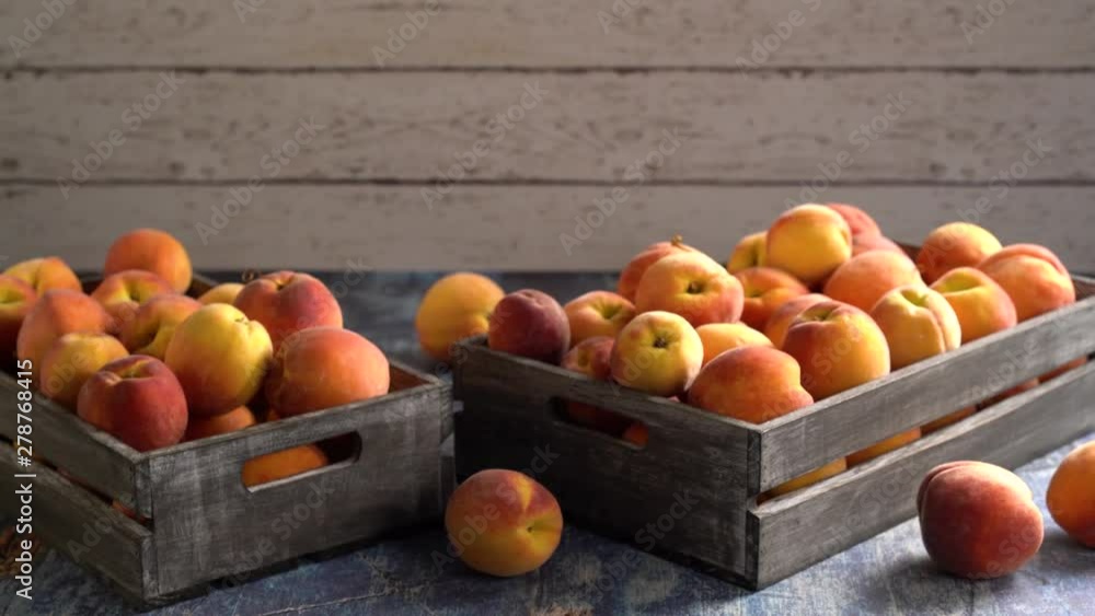 Camera slides left showing fresh peaches in rustic wood crates on blue table top and white painted wood background. Camera slides left showing fresh peaches in rustic wood crates on blue table top and white painted wood background.