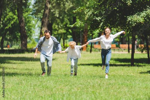 excited family holding hands and running in park during daytime