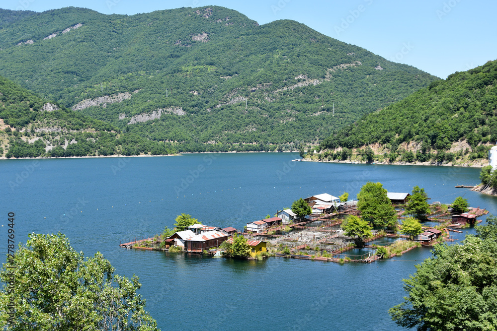 Fototapeta premium Floating fish farm in the blue waters of Vacha Lake, Rhodope Mountains, Bulgaria