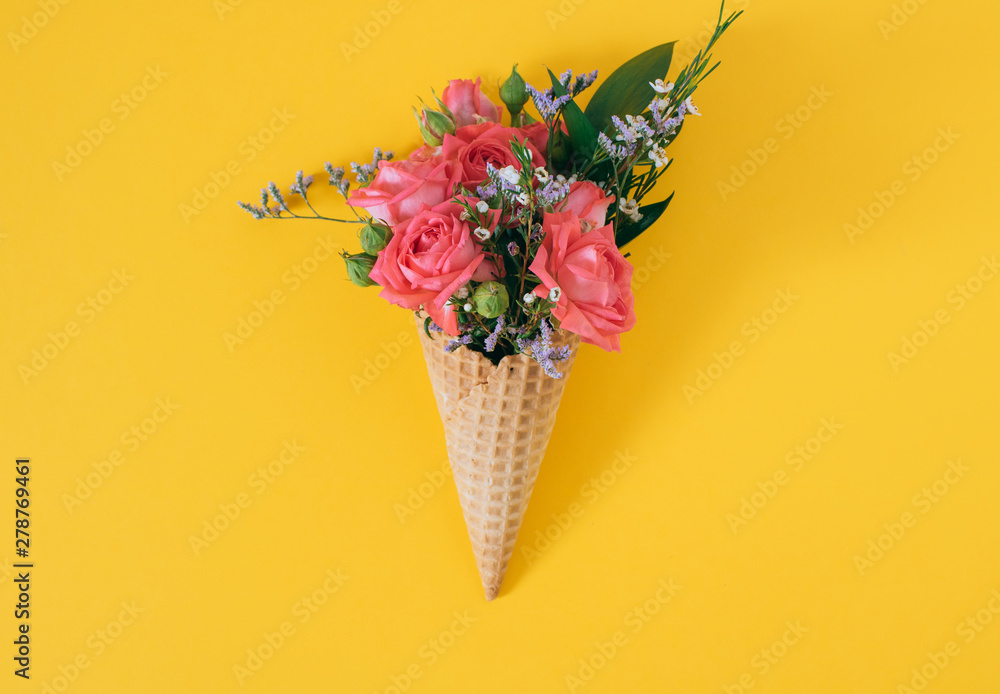 Flat lay Ice Cream Cone with colorful bouquet on yellow background, copy space
