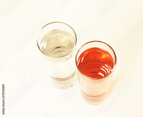 Two glasses of red and transparent liquid on white background, São Paulo, Brazil photo