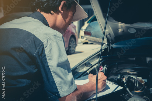 Professional car repair technicians inspect the engine according to the checklist documents to ensure that they are inspected according to the standards of the service center.