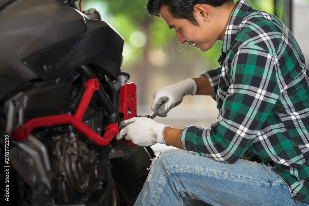 Cropped view of motorcycle mechanic using a wrench and socket on a motorcycle