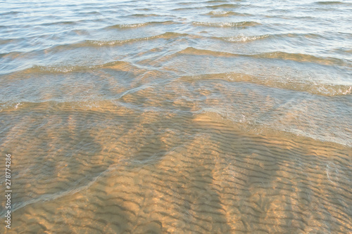 Soft wave of the water on the sandy beach. Waves of sand under the water
