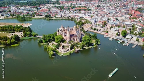 Aerial, reverse, drone shot, tilting away from the Schwerin Castle and the city, on a sunny summer day, in Germany photo