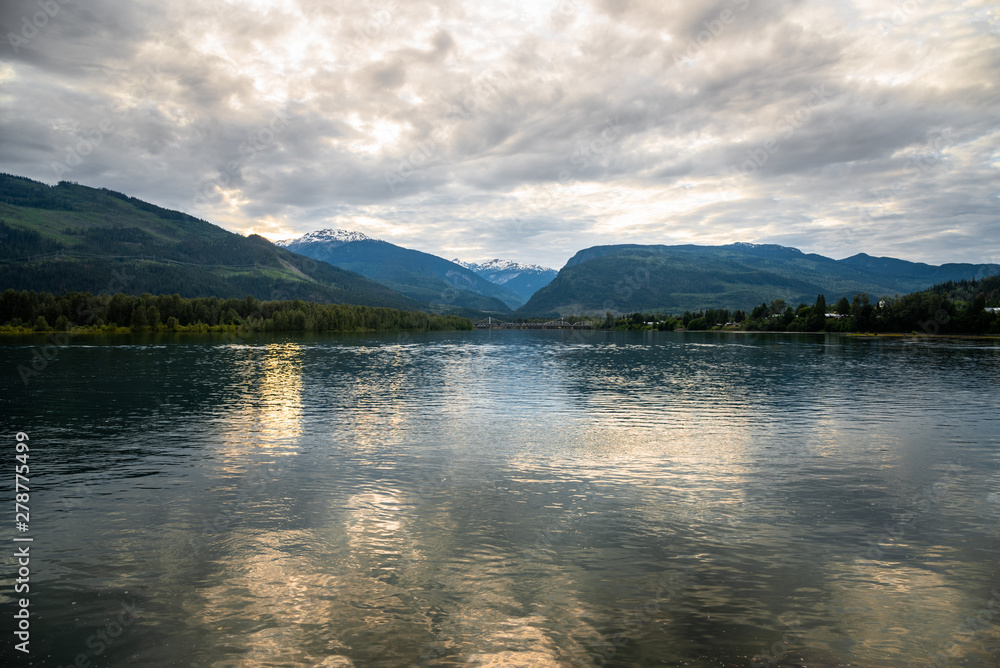 Beautiful mountain scenery at sunset with a wide river in foreground. Revelstoke, BC, Canada.