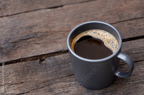 Black coffee in a blue-grey ceramic mug isolated on rustic dark brown wood table. Space for text.