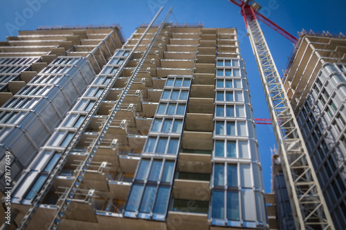 High-rise building under construction. The site with cranes against blue sky. Tilt shift focus