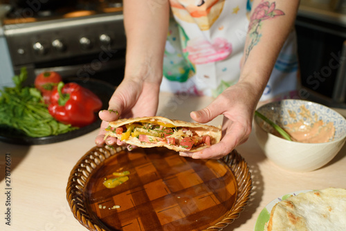 Girl cook cooks delicious tortilla pork and fresh vegetables