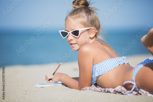 Little girl is painting on the beach. Summertime